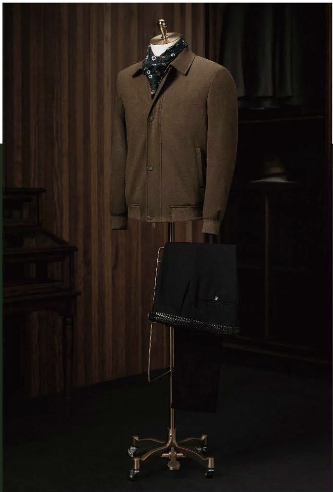 A dark brown casual jacket with a collar and 4-button fastening, displayed on a mannequin, with black trousers and a waistcoat in the background, set against a wooden background