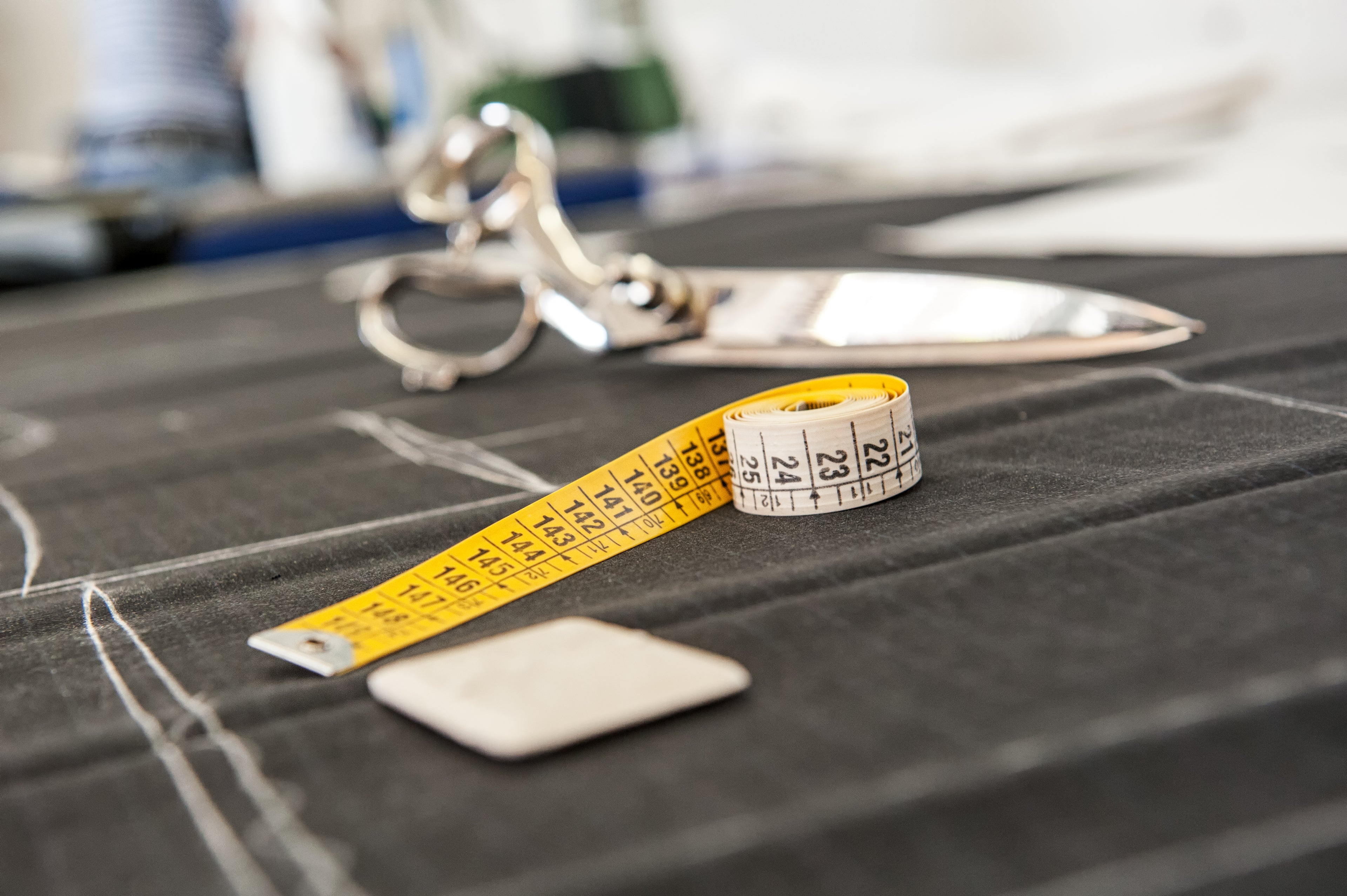 Professional tailoring tools with measuring tape and scissors on pinstripe fabric - fast track cutting services available - A Hand Tailored Suit