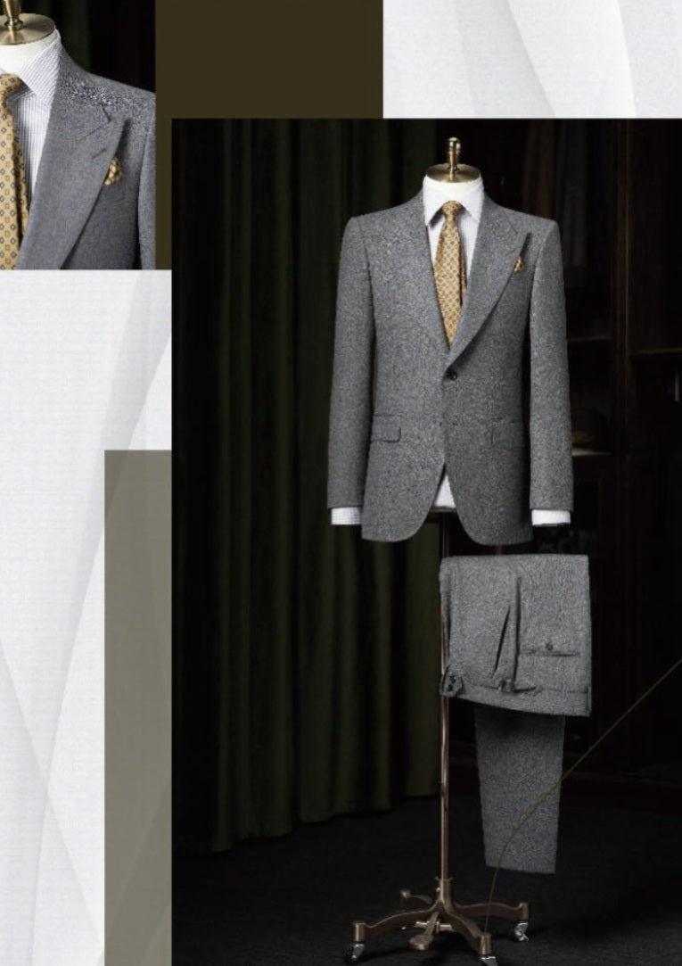 Grey suit on a mannequin with a gold tie against a dark curtain background