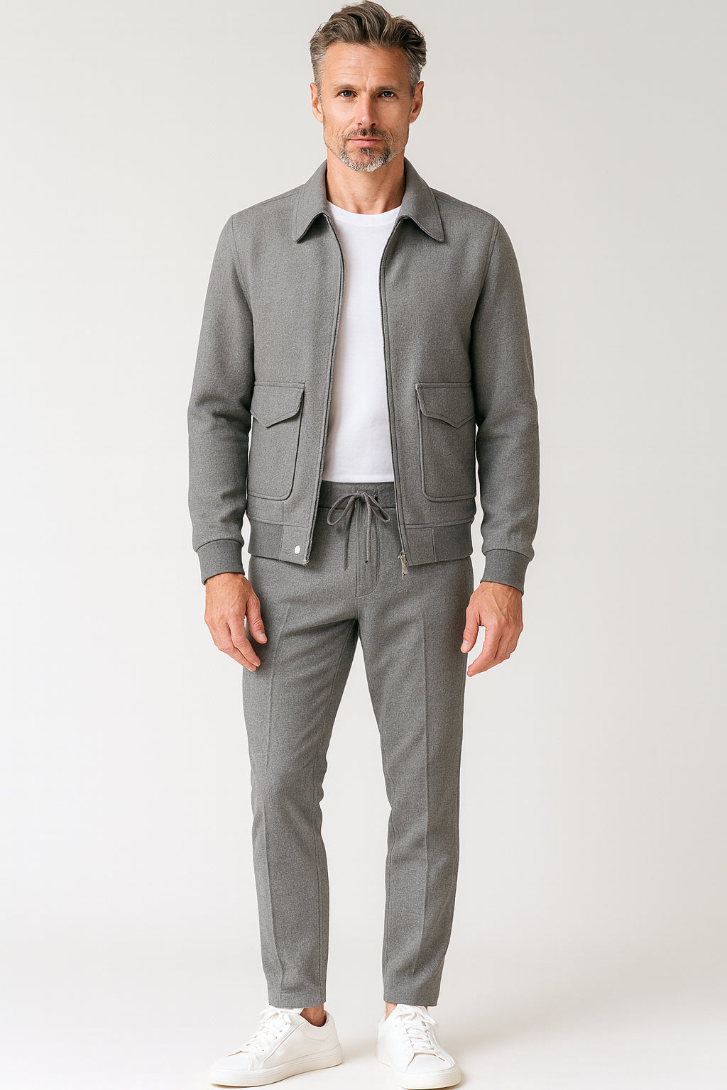 Man wearing a gray jacket and pants with a white shirt on a light gray background