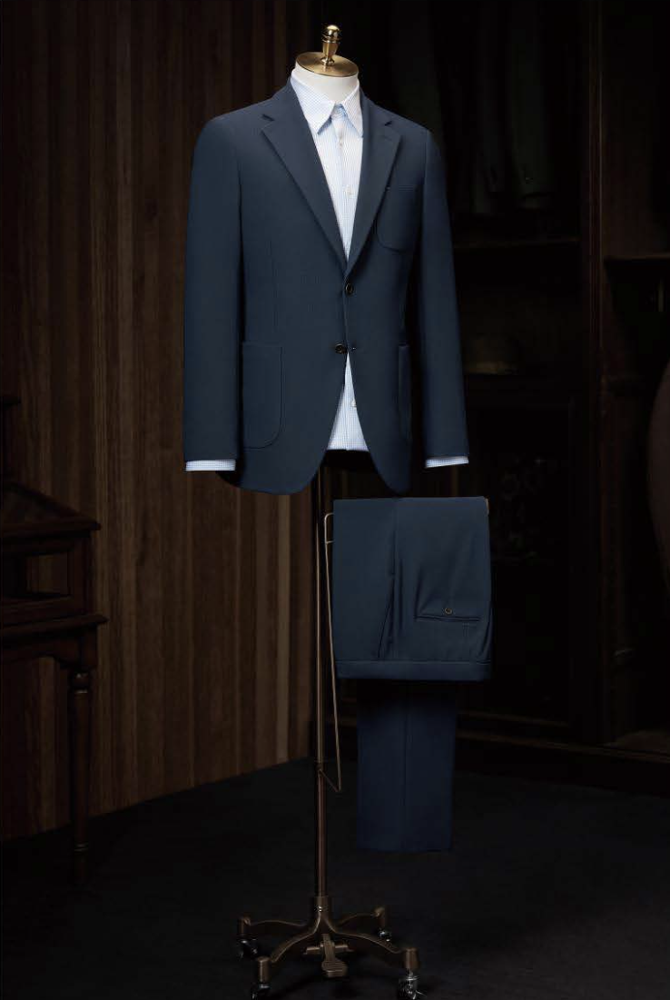 A mid blue textured casual single breasted jacket displayed on a mannequin with matching trousers, featuring a notched collar, front buttons, and a breast pocket.