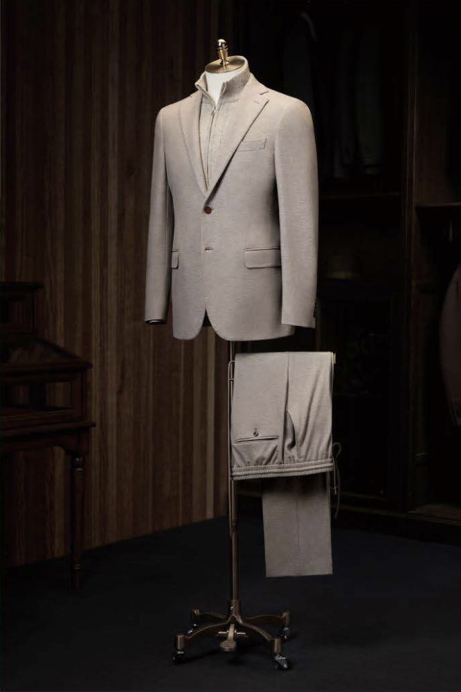 A stone casual jacket and plus stone trousers displayed on a mannequin, with the jacket featuring a single button, notched lapels, and the trousers having a plain front waistband and elasticated cross-back pockets.