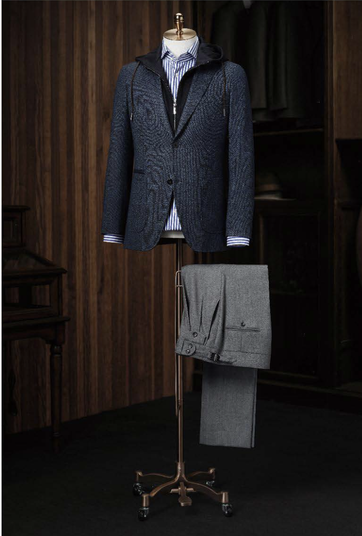 A blue textured casual single breasted jacket displayed on a mannequin with grey trousers, showcasing features such as a peaked lapel, front pockets, and a waistband side adjuster.
