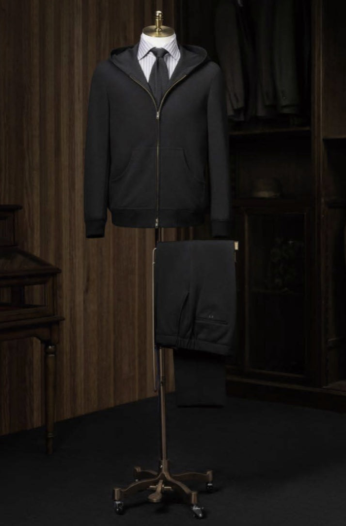 A black casual hooded zip jacket displayed on a mannequin with trousers, showcasing a slim fit and front zip detail
