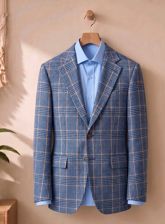 A blue plaid blazer jacket with a light blue dress shirt, hanging on a wooden hanger against a warm beige wall.