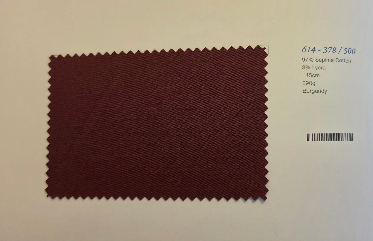 A burgundy fabric swatch with serrated edges displayed on a light beige background, next to printed text showing color and composition details.