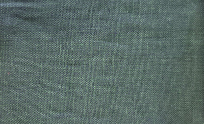 A close-up fabric swatch showing a dark green woven textile with a visible zigzag-cut fabric edge, alongside partial neighboring swatches in light wood and dark brown.