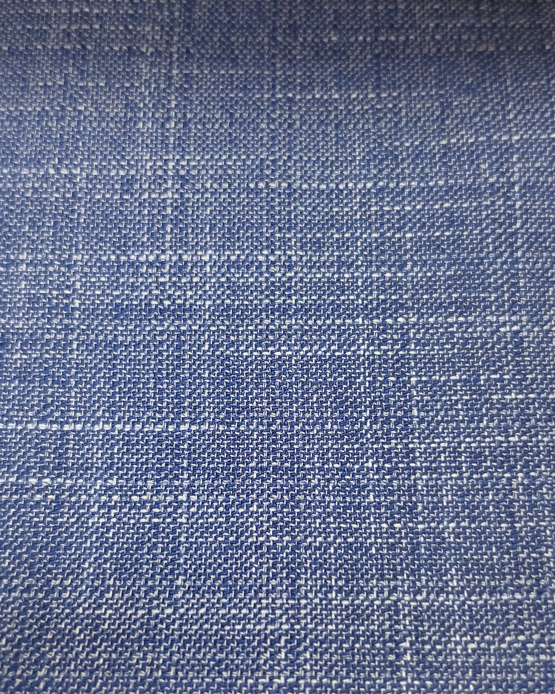A close-up of a blue woven fabric with a subtle white plaid pattern.