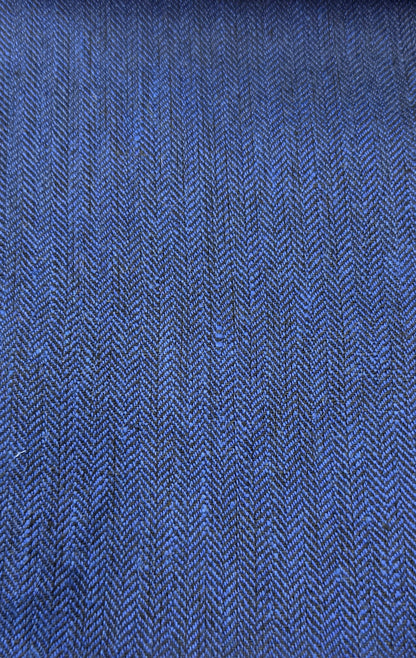 A close-up of a blue woven fabric with a visible herringbone texture, shown against a light wood background.
