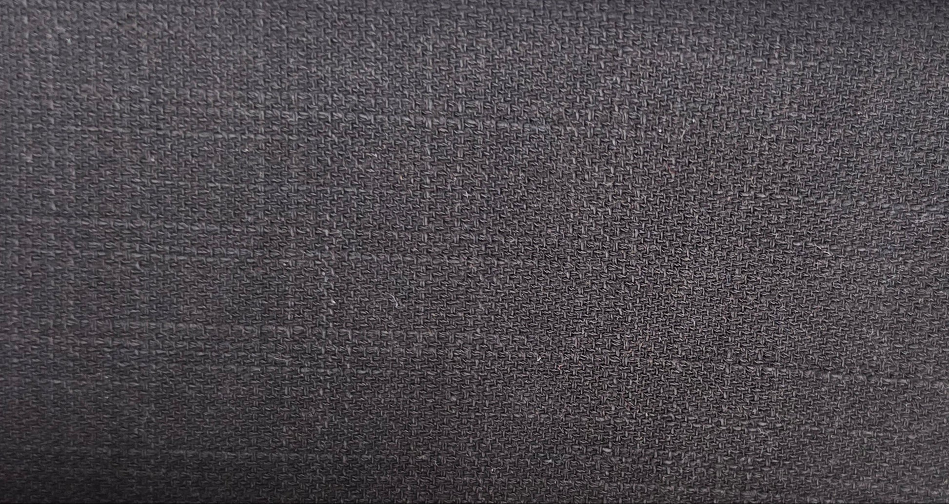 A close-up of a dark charcoal gray textured fabric with a subtle woven grid pattern.