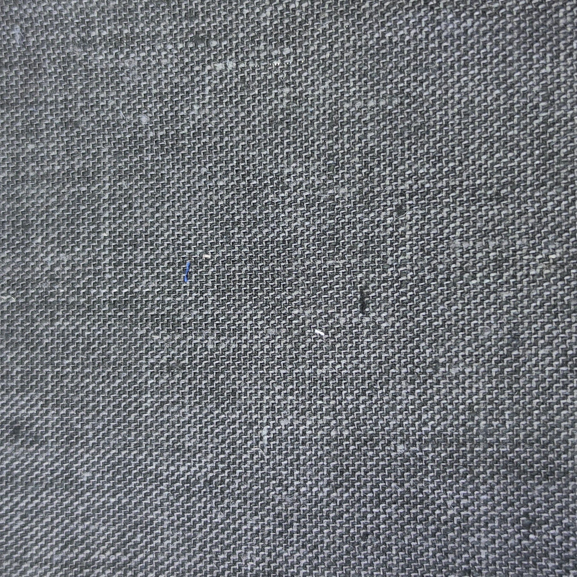 A close-up of a dark gray woven fabric swatch with a visible zigzag-cut edge, shown against a light wood background.