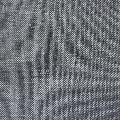 A close-up of a dark gray woven fabric swatch with a visible zigzag-cut edge, shown against a light wood background.
