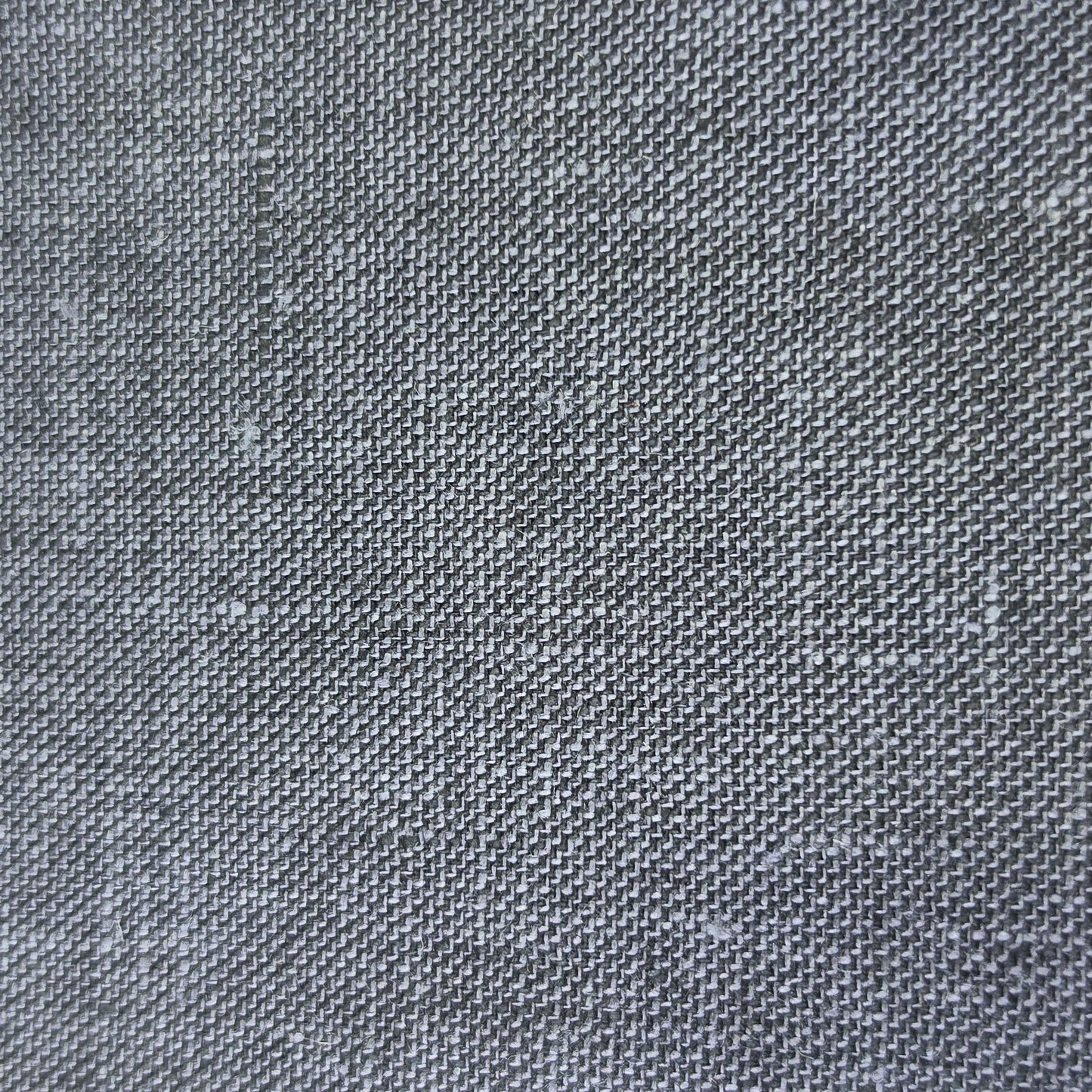 A close-up of a dark gray woven fabric swatch with a visible zigzag cut edge, placed against a light wood background.