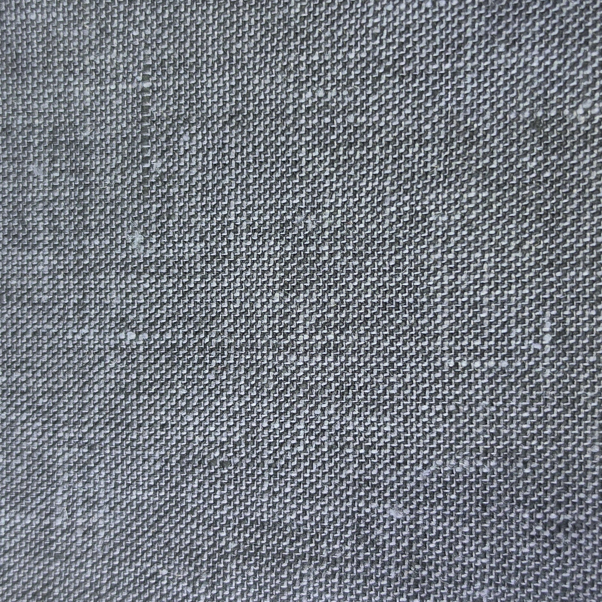A close-up of a dark gray woven fabric swatch with a visible zigzag cut edge, placed against a light wood background.