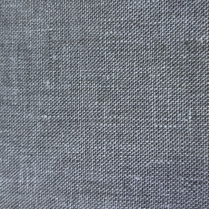 A close-up of a dark gray woven fabric swatch with a visible zigzag cut edge, placed against a light wood background.