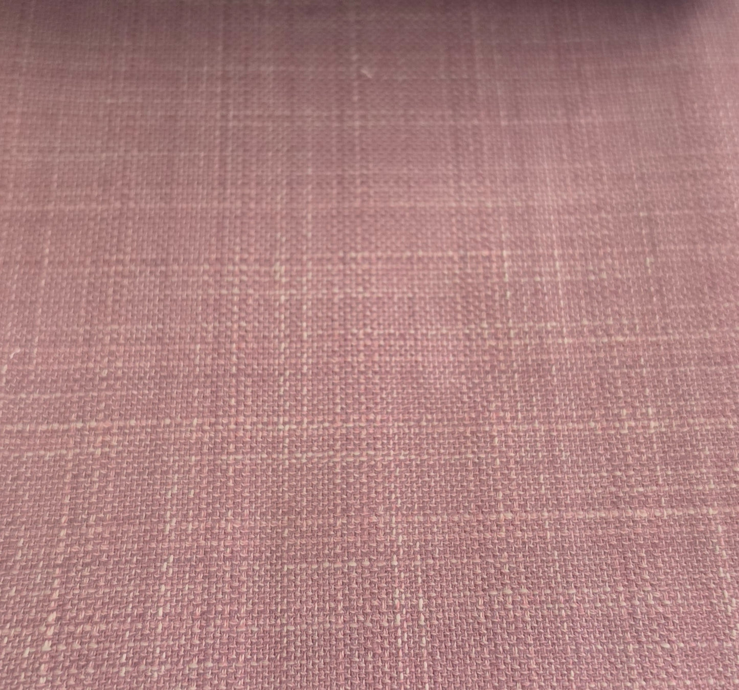 A close-up of a dusty rose pink woven fabric with a subtle grid pattern.