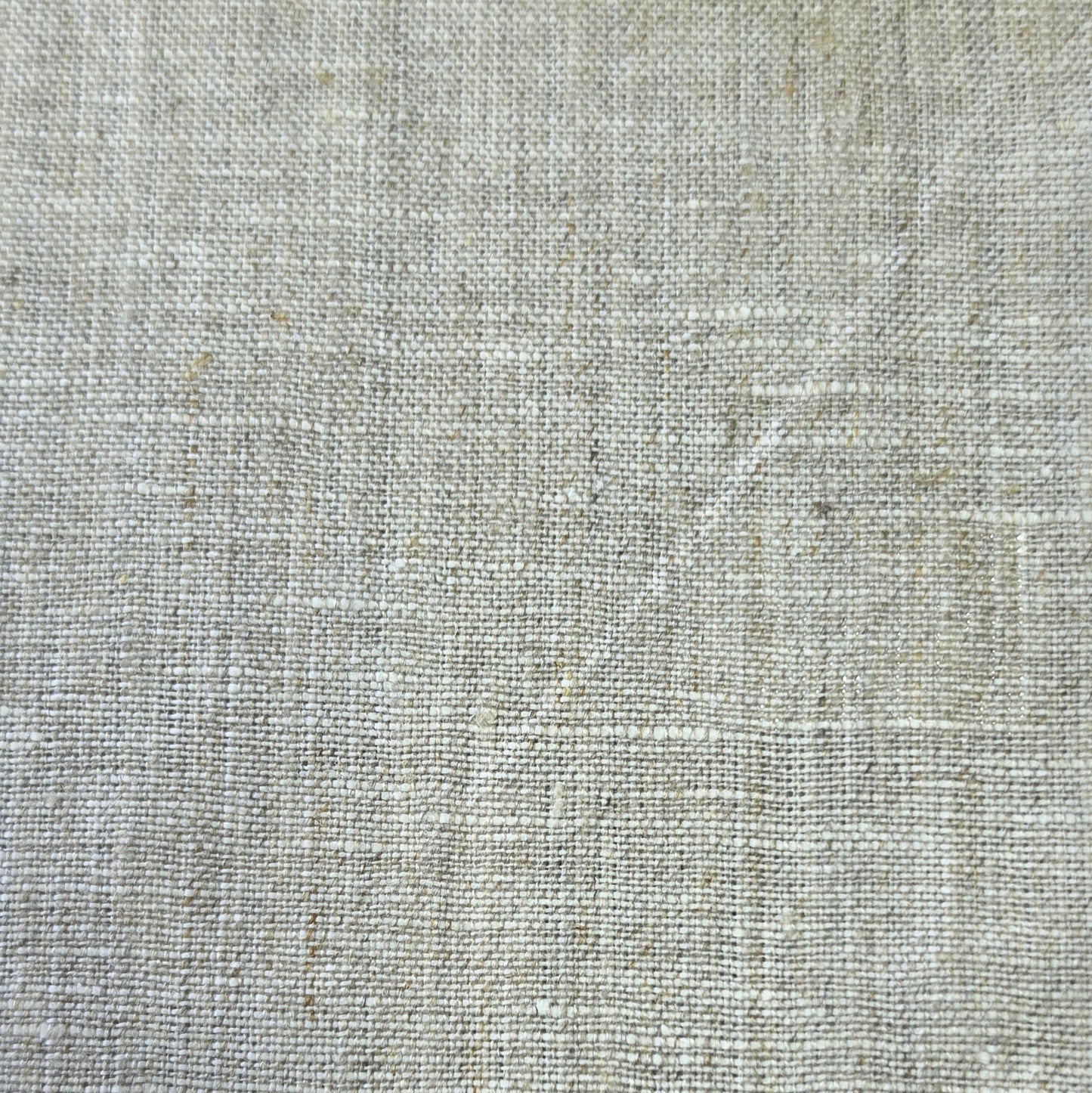A close-up of a light beige linen fabric texture with a natural woven pattern.