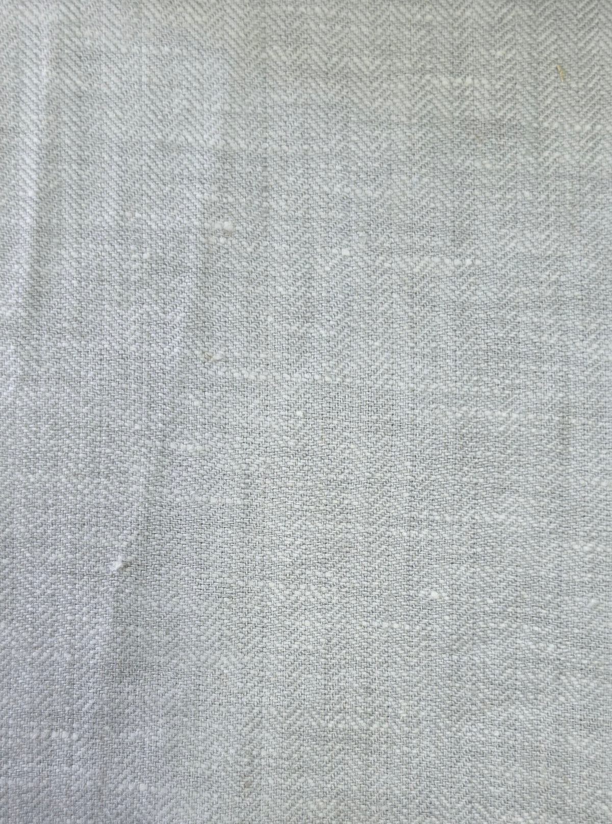 A close-up of a light gray and white herringbone woven fabric texture.