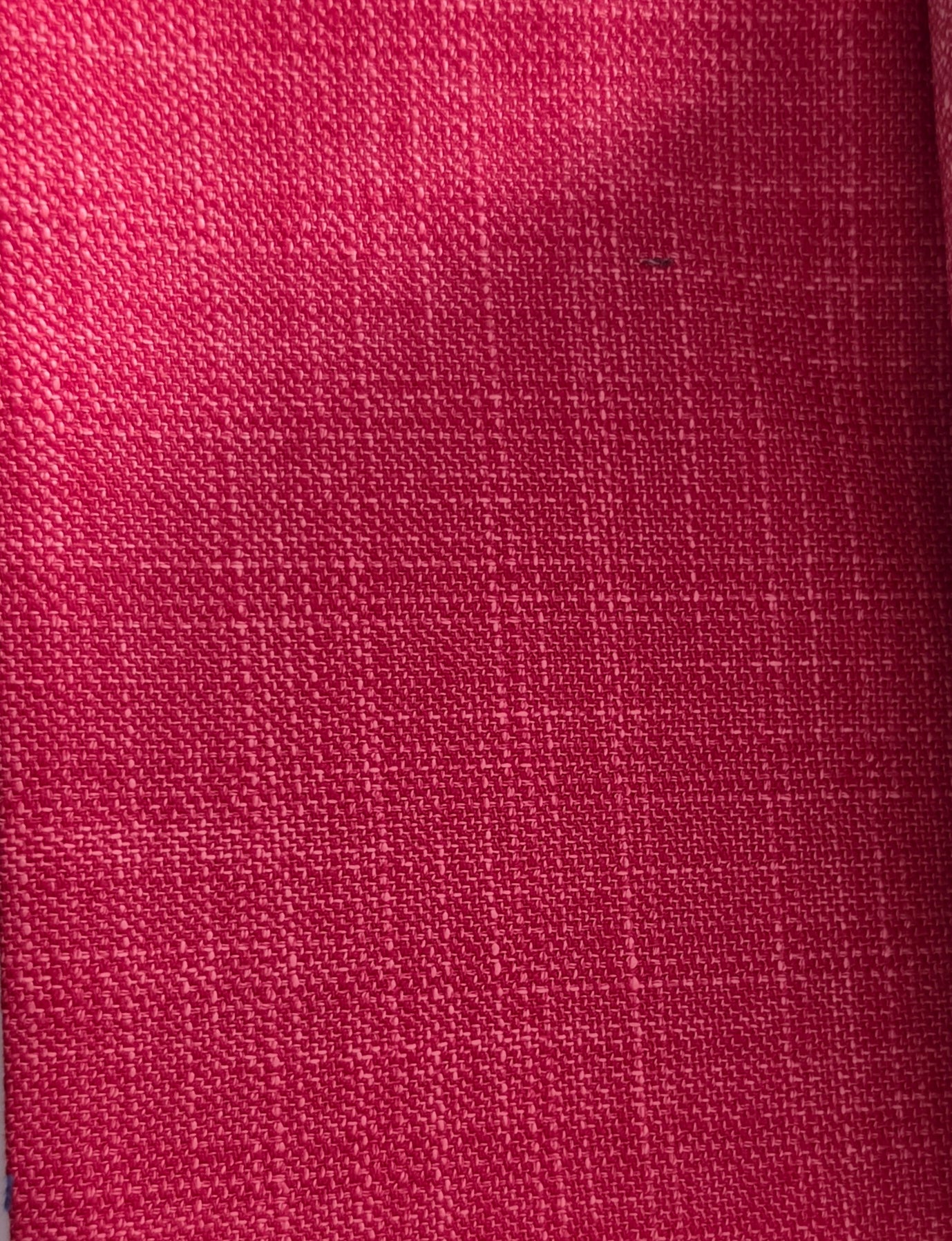 A close-up of a textured woven fabric in a rich magenta pink color, showing the detailed linen-like weave pattern.