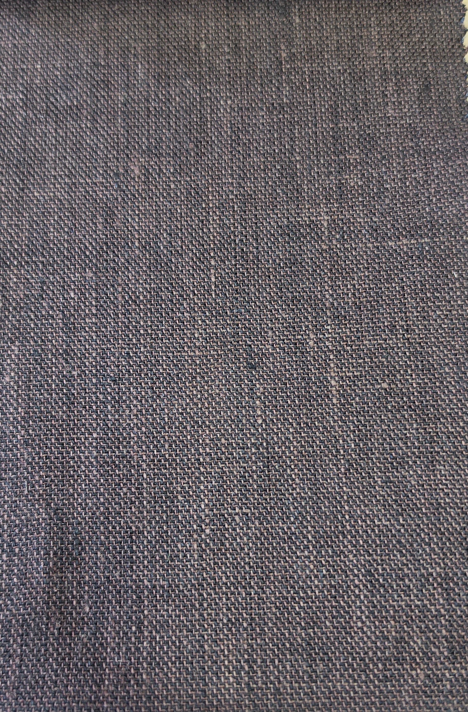 A close-up of a woven fabric swatch in a dark brown color, showing the texture and weave pattern, with a light wood surface visible at the bottom.