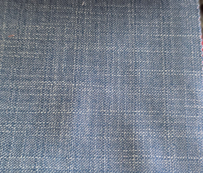 A close-up of a woven fabric texture in a dusty slate blue color with white threads forming a subtle grid pattern.