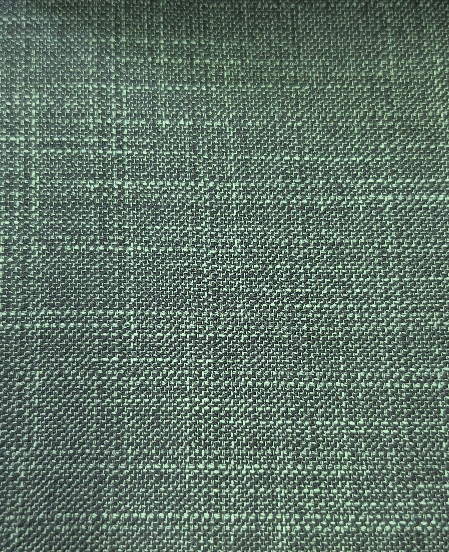 A close-up of a woven fabric texture in a muted sage green color with a subtle plaid pattern.