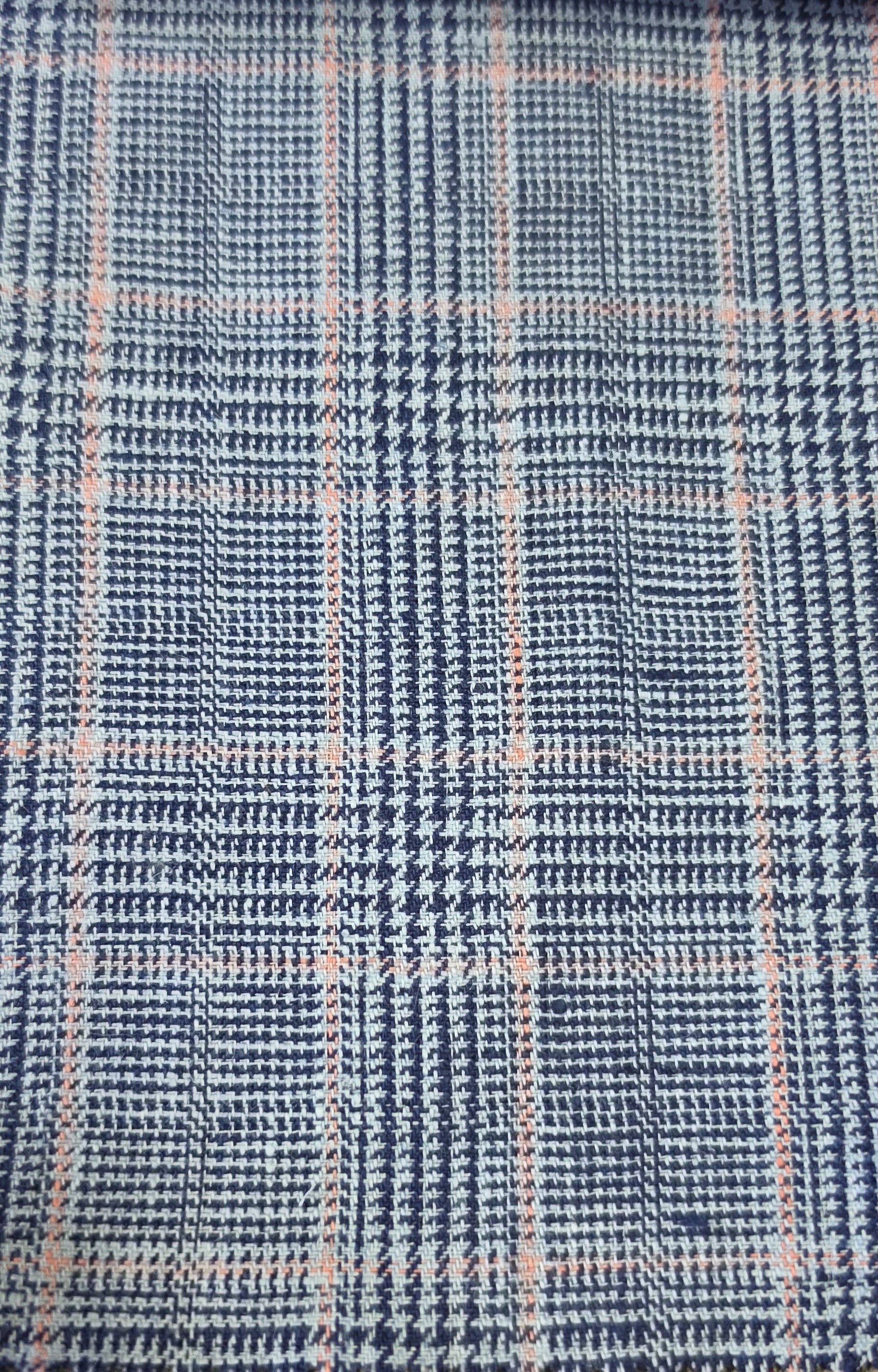 A close-up of a woven fabric with a blue and white houndstooth pattern overlaid with a light pink plaid grid.