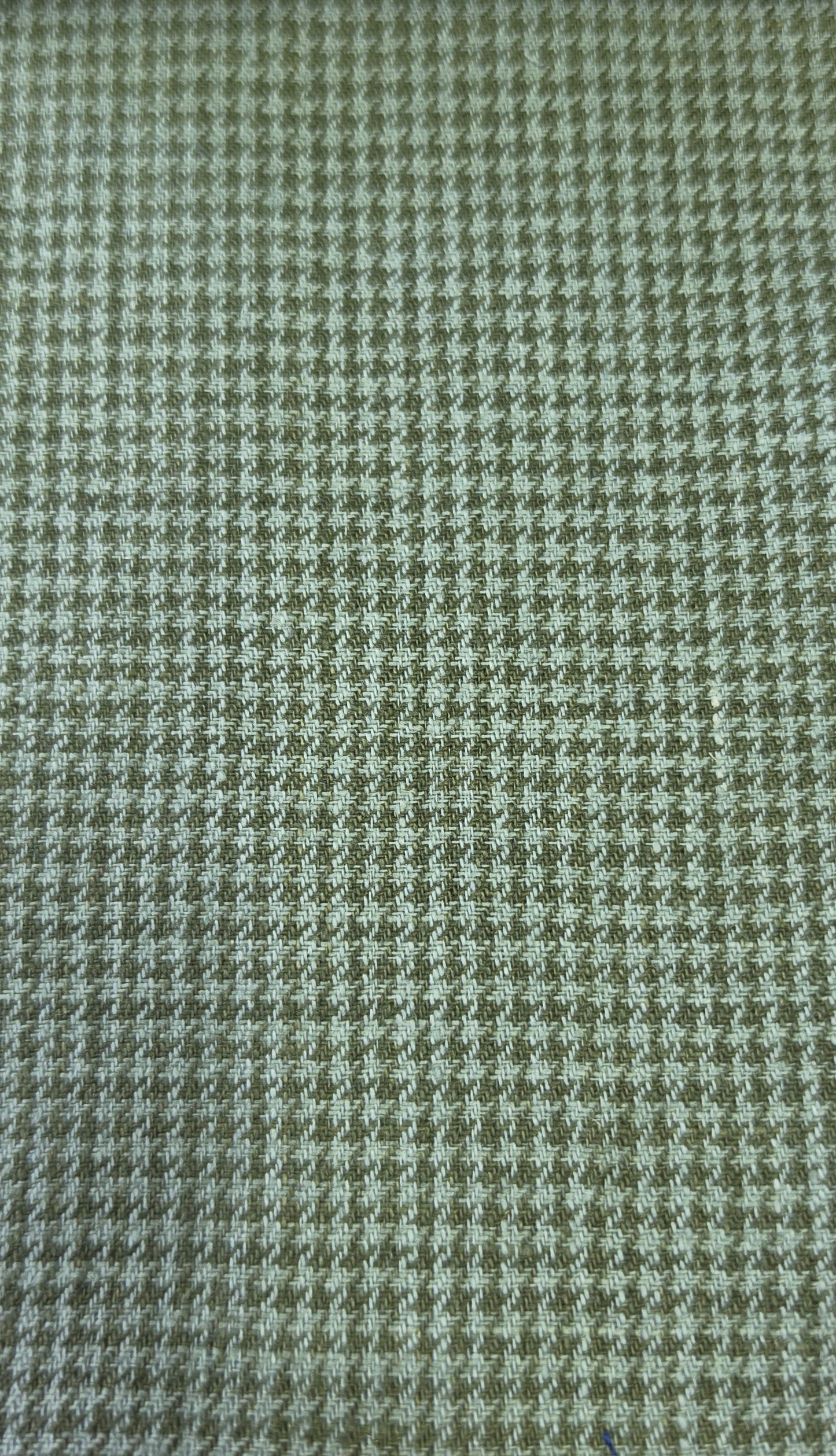 A close-up of a woven fabric with a small-scale houndstooth pattern in muted olive green and off-white.