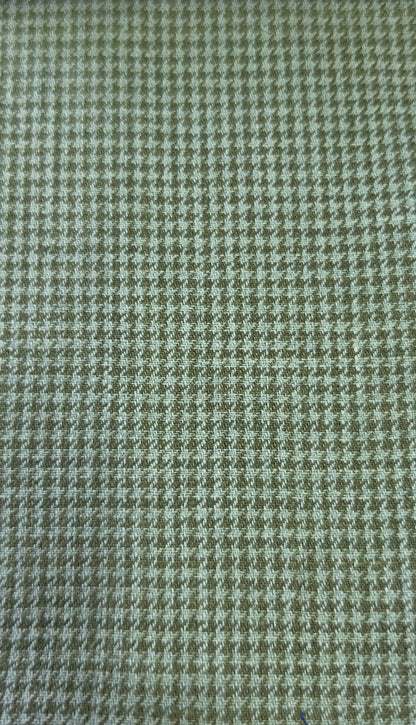 A close-up of a woven fabric with a small-scale houndstooth pattern in muted olive green and off-white.
