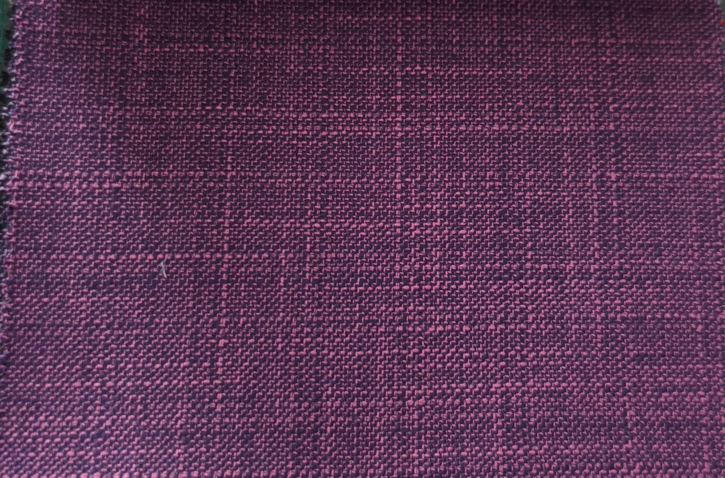 A close-up of a woven fabric with a subtle windowpane plaid pattern in deep purple and magenta tones.