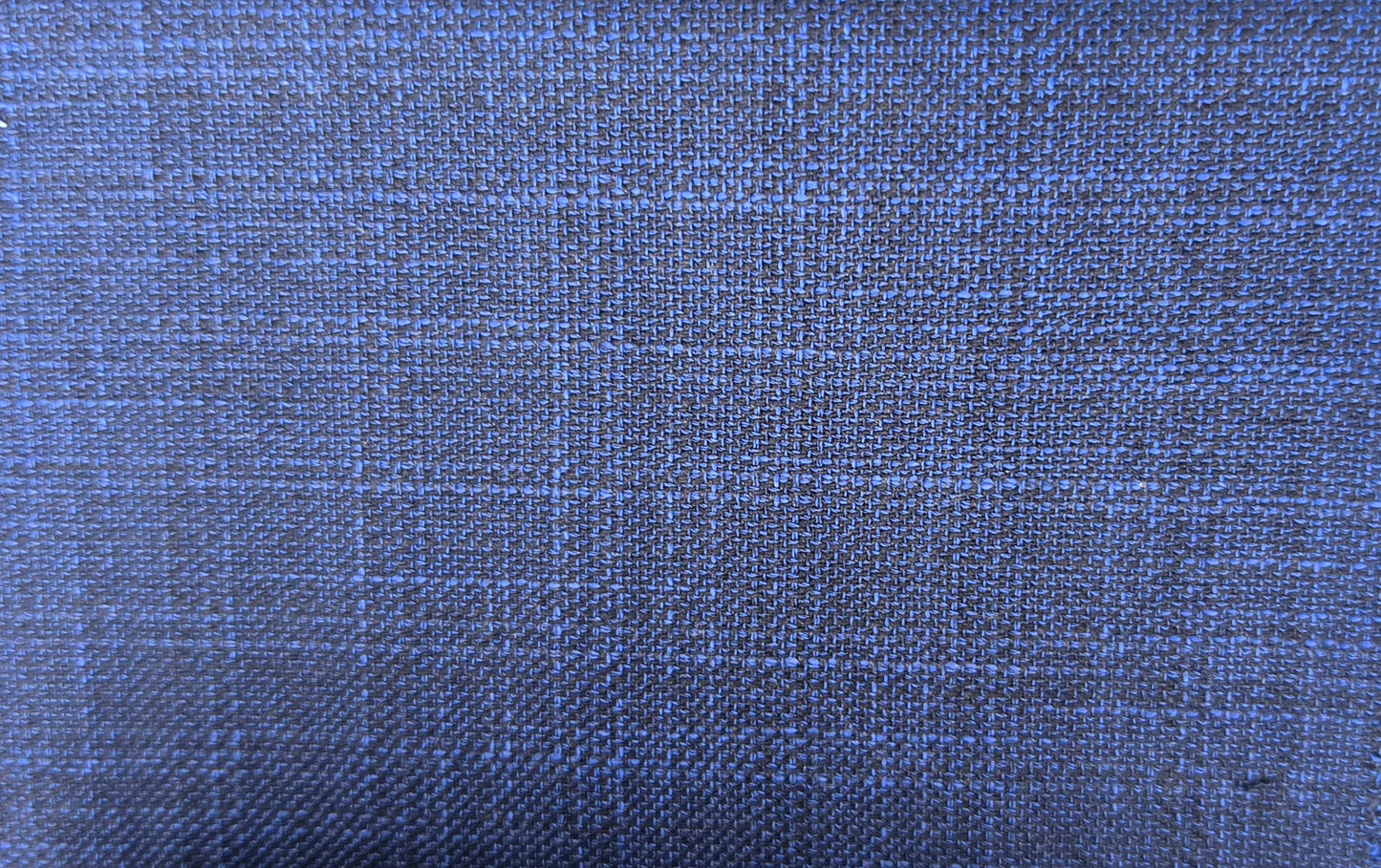 A close-up of woven fabric texture in a medium-to-dark blue color with subtle lighter blue and gray plaid lines.