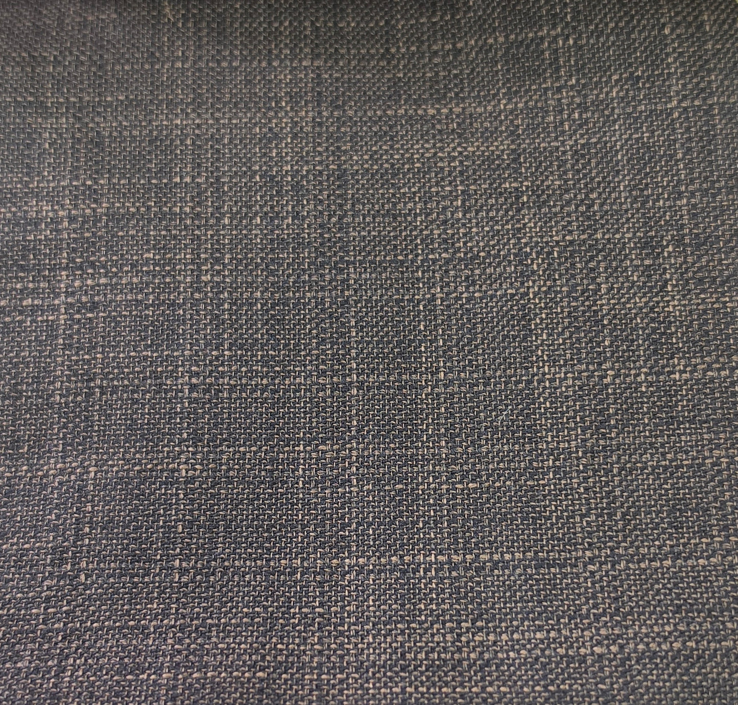 A close-up of woven fabric with a subtle plaid pattern in dark charcoal gray and light beige threads.