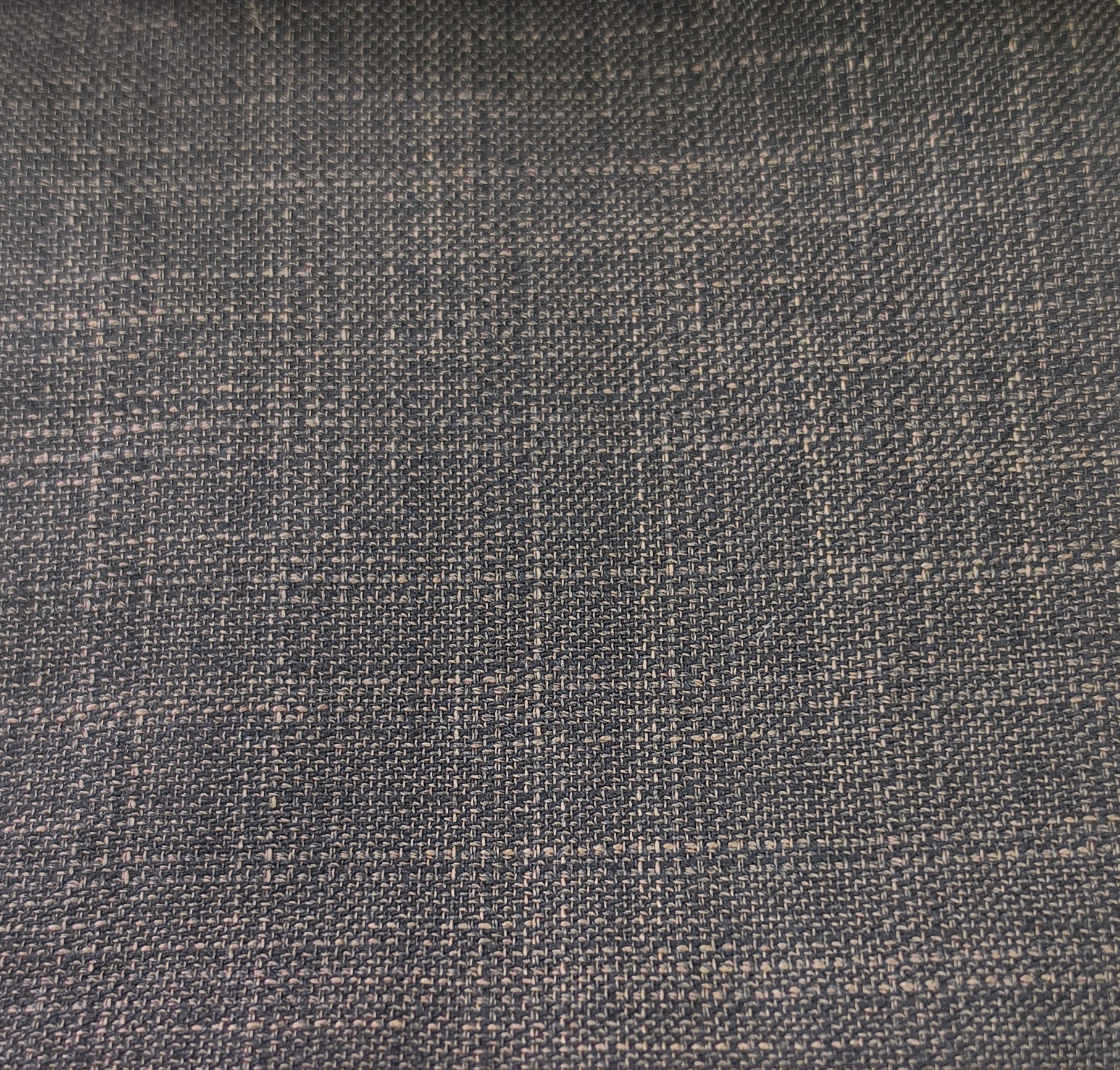 A close-up of woven fabric with a subtle plaid pattern in dark charcoal gray and light beige threads.
