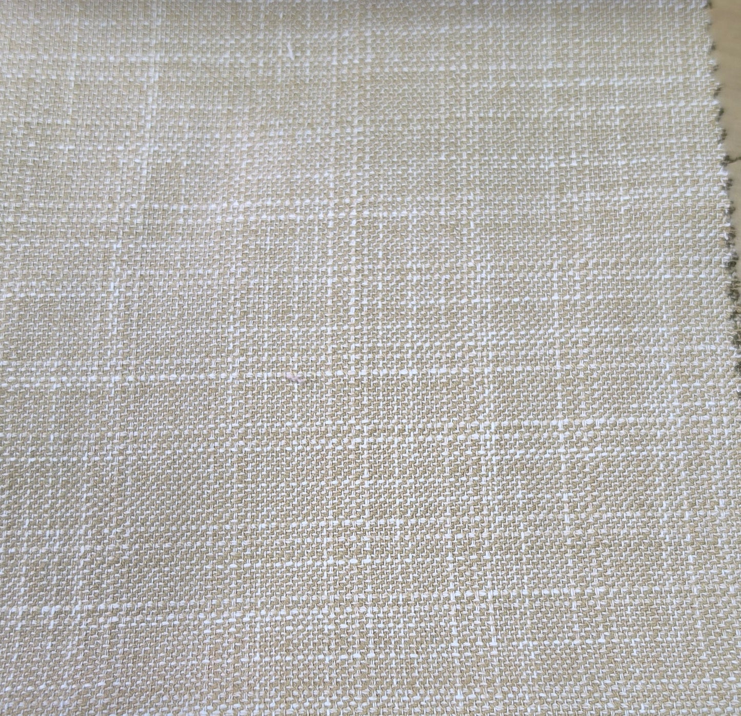 A close-up of woven fabric with a subtle plaid pattern in light beige and off-white, showing the texture and weave detail.