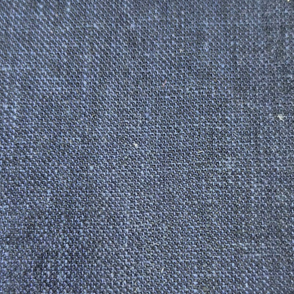 A close-up texture shot of dark indigo denim fabric, showing the detailed weave and subtle heathered blue and gray tones.