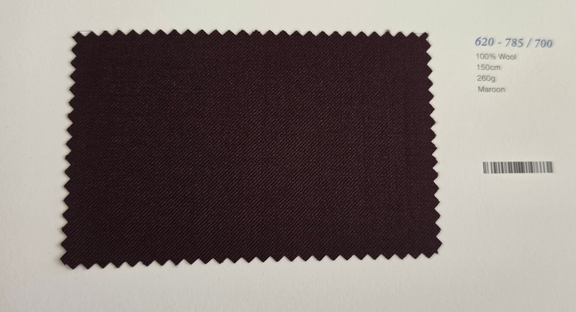 A dark Maroon fabric swatch with serrated edges, displayed on a white background next to printed fabric specifications.