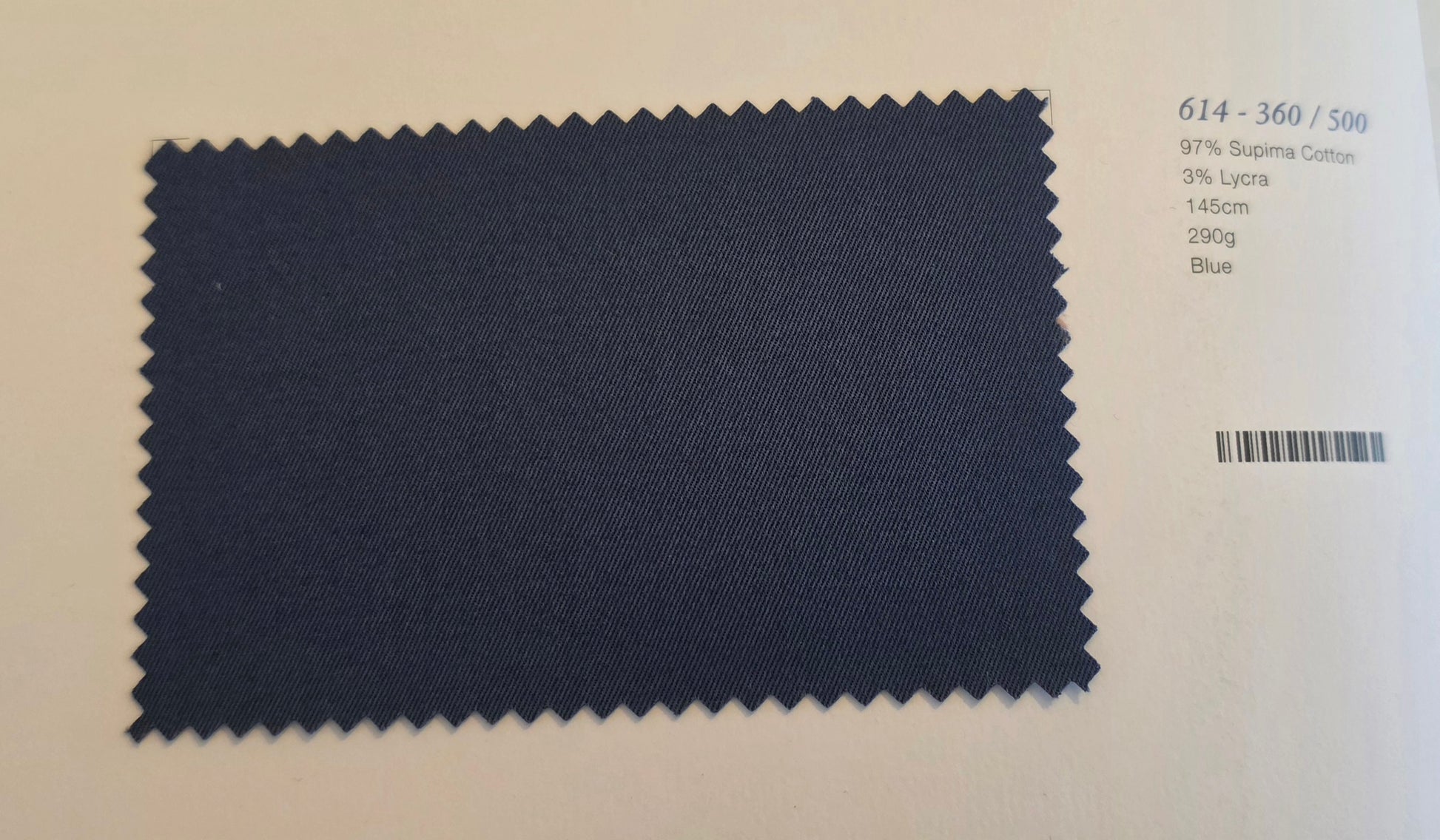 A dark blue fabric swatch with serrated edges on a white background, next to printed text showing color code 614-360/500 and fabric composition details.