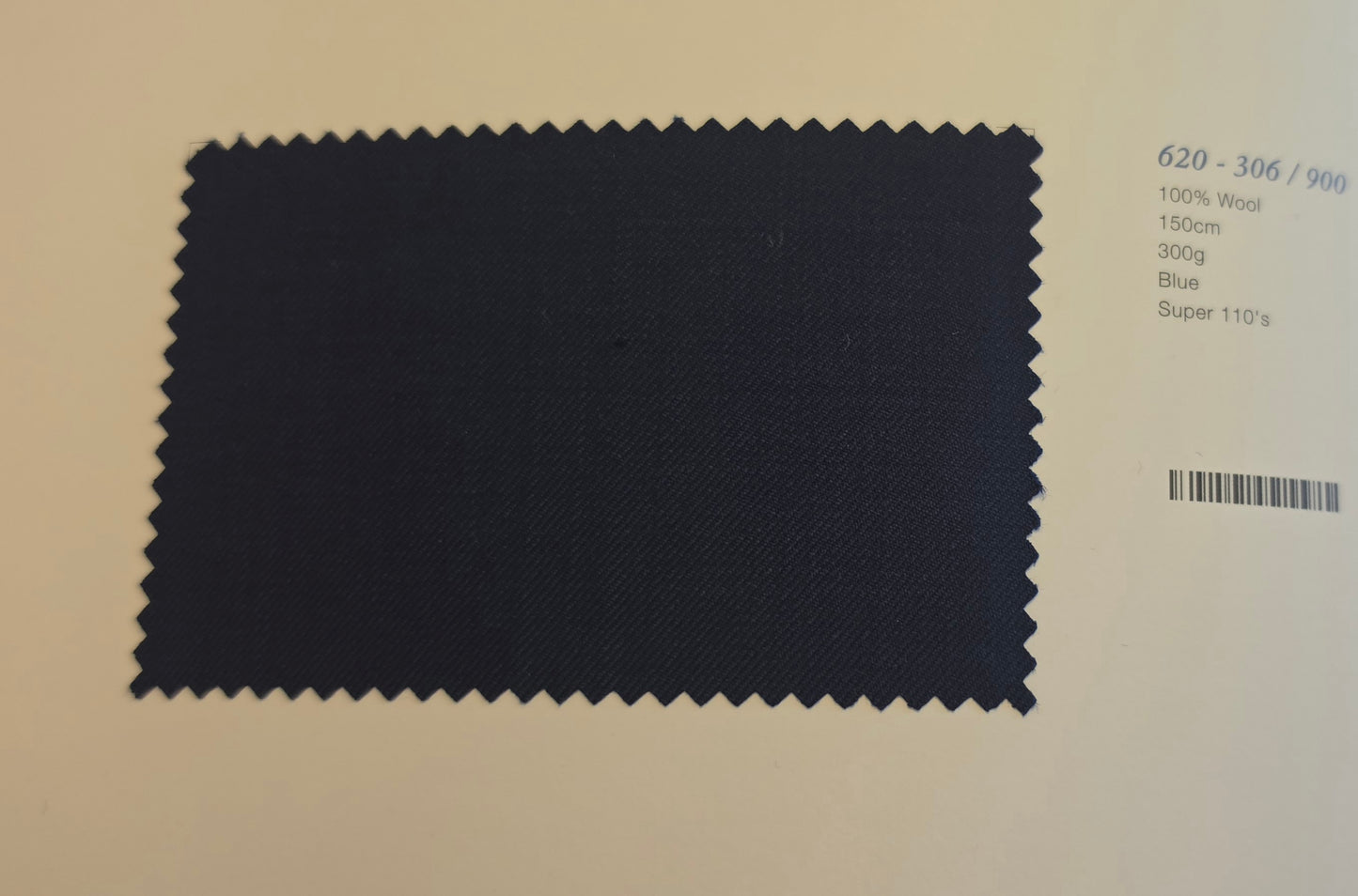 A dark blue fabric swatch with zigzag-cut edges displayed on a light beige background, next to printed text specifying material and color details.