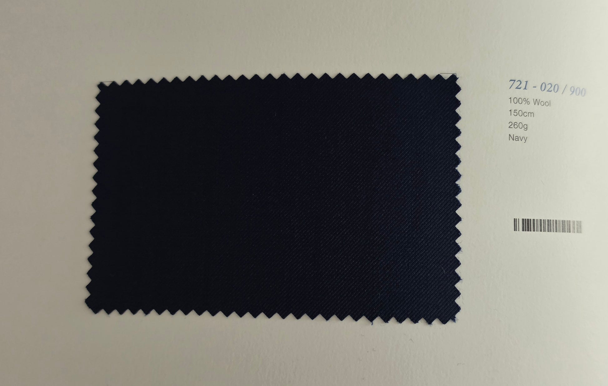 A dark navy blue fabric swatch with serrated edges displayed on a white background next to printed text identifying the color as Navy.