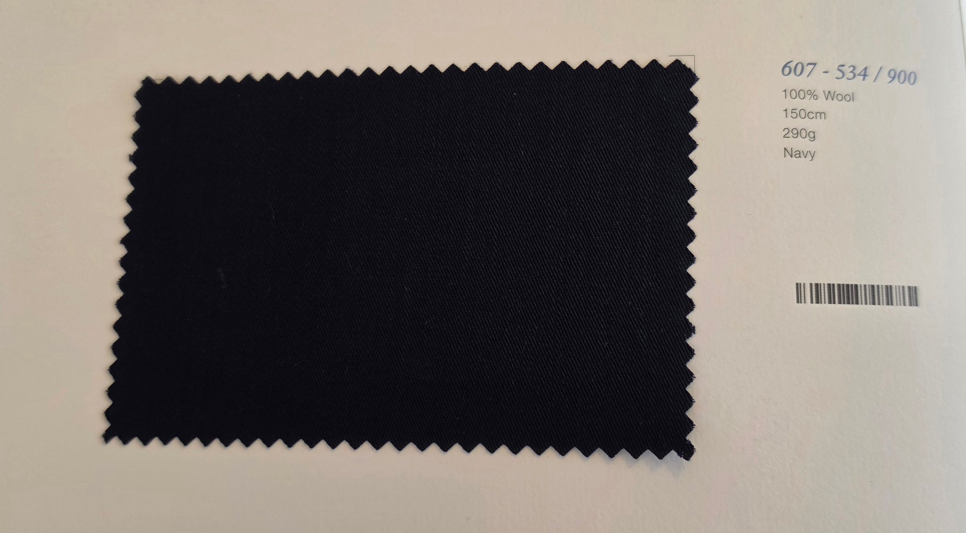 A dark navy fabric swatch with serrated edges on a white background, next to printed text showing color code 607-534/900, 100% Wool, 150m, 290g, and Navy.