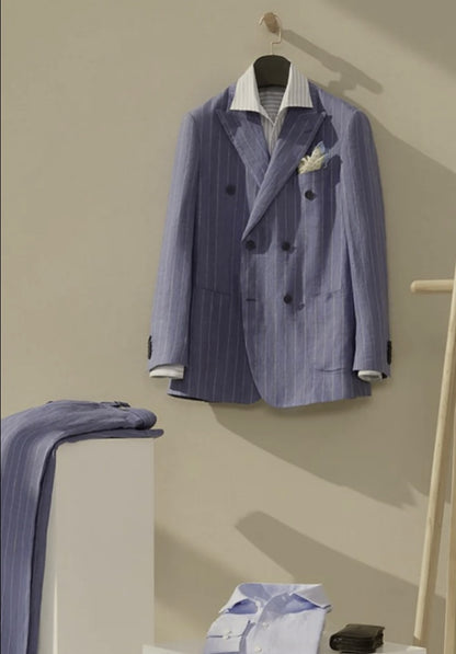 A double-breasted, blue chalk stripe jacket hanging on a hanger, with a waistcoat and a pair of trousers displayed in the foreground.