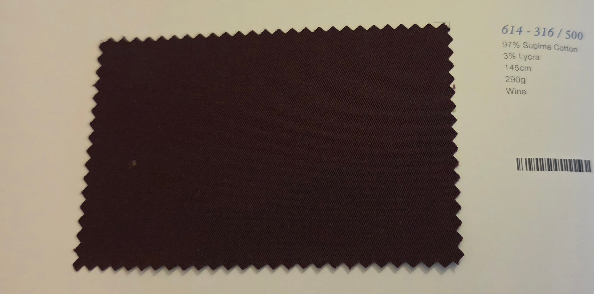 A fabric color swatch card showing a dark wine-colored material sample with serrated edges, alongside printed color code text and a barcode on a white background.