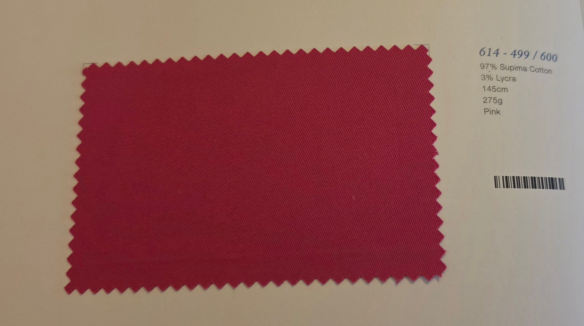 A fabric color swatch card showing a deep pink-red textured cotton swab with serrated edges, printed with code 614-499/600 and material details on a light background.