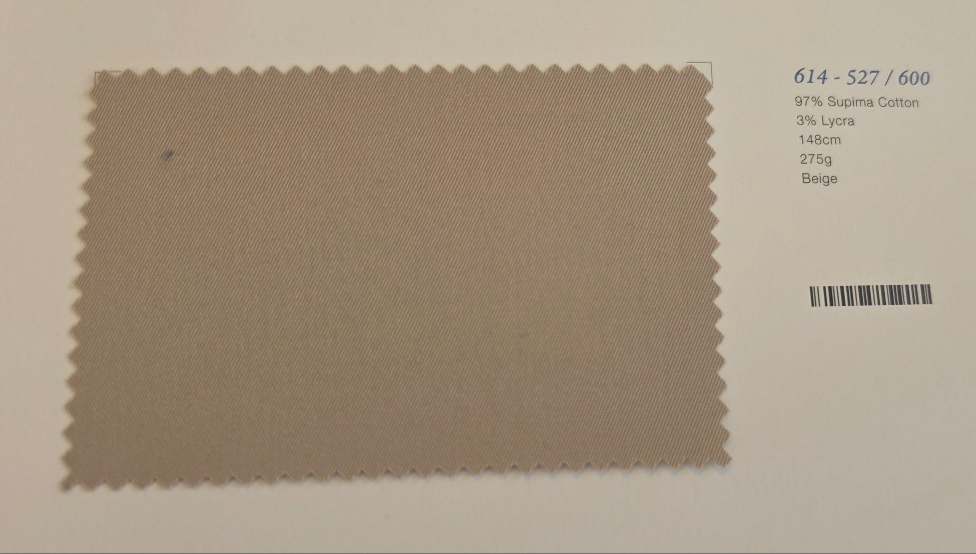 A fabric color swatch card showing a textured taupe-beige swatch with a serrated edge, printed on a white card with a barcode and text below.