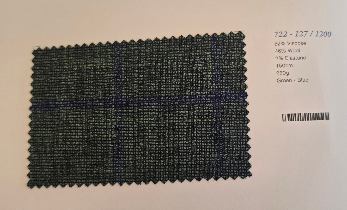 A fabric swatch card showing a dark green and blue plaid pattern, with printed specifications on the right side against a light background.
