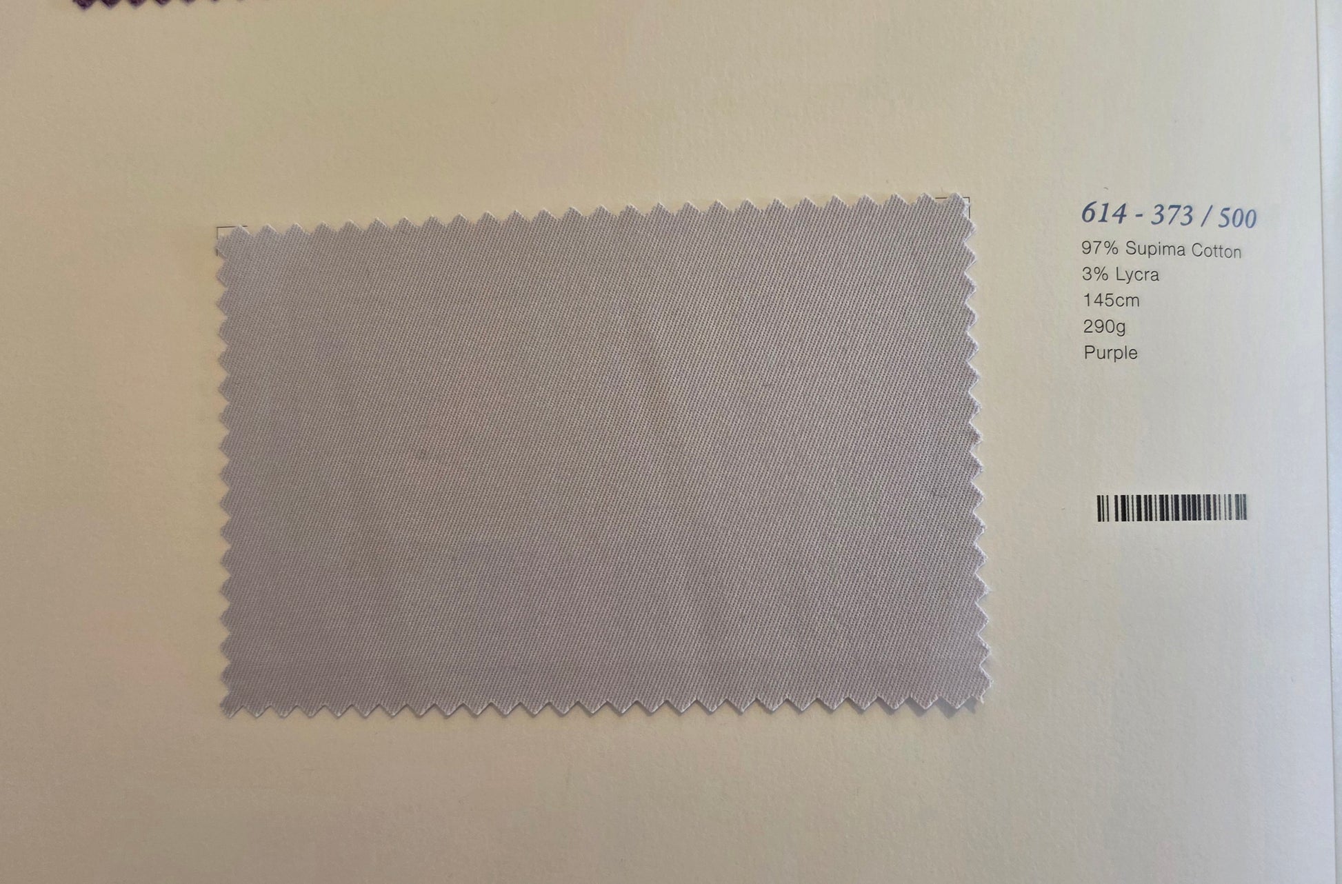 A fabric swatch card showing a light purple/lavender textured cloth with serrated edges, alongside printed text including '614 - 373 / 500' and 'Purple'.