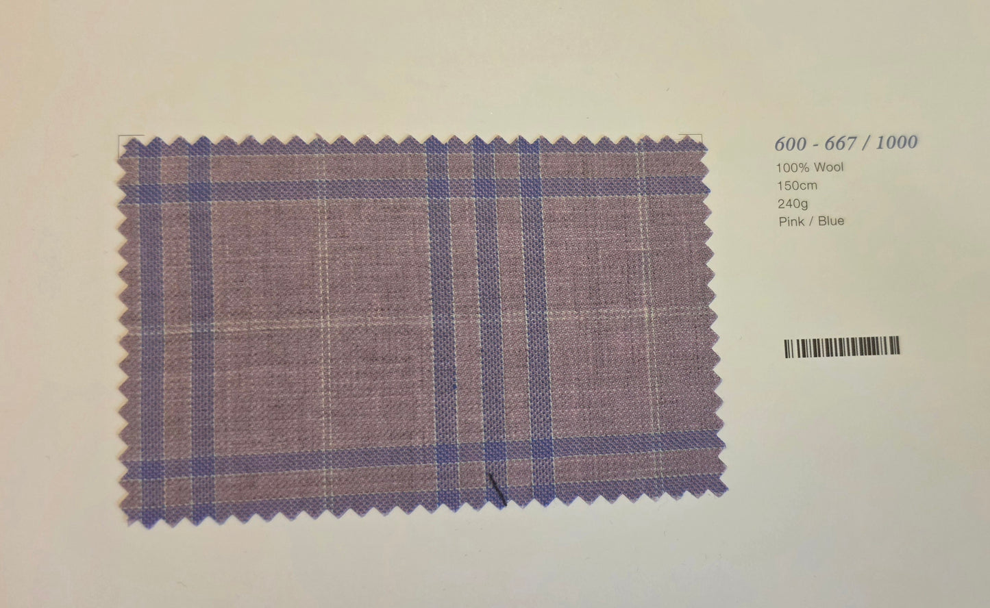 A fabric swatch card showing a purple and blue plaid pattern on a light background, with printed text on the right indicating wool composition and color details.