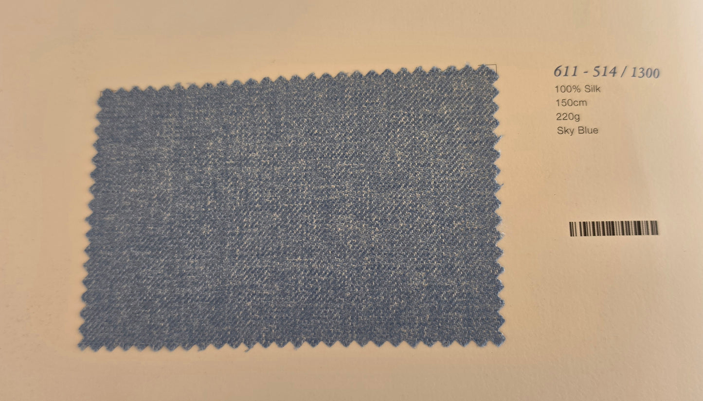A fabric swatch card showing a textured sky blue woven material sample with printed details including code 611-514/1300, 100% silk, 150cm, 220g, and sky blue.