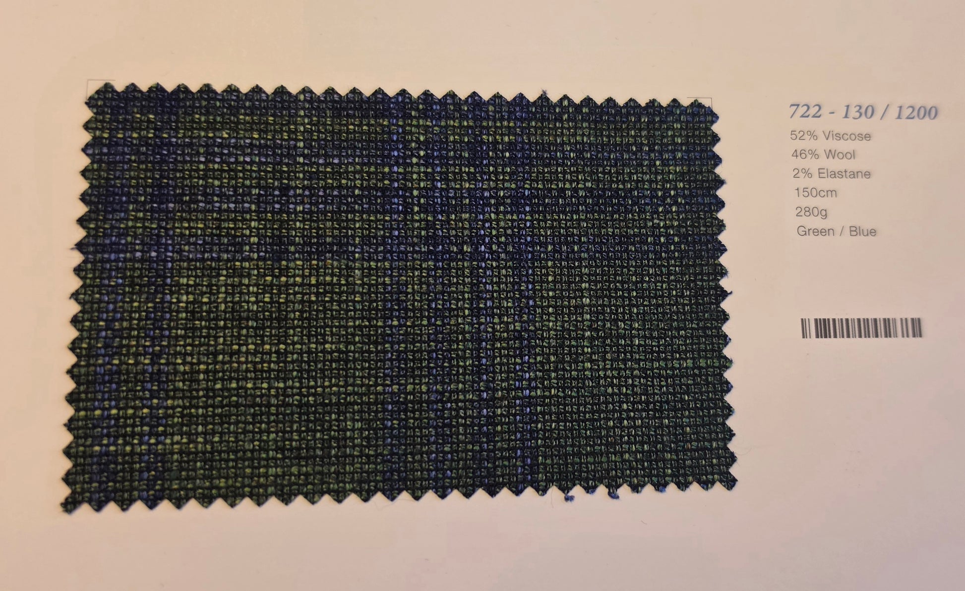 A fabric swatch card showing a textured woven material in a green and blue plaid pattern, with printed text on the right side detailing the composition and color.