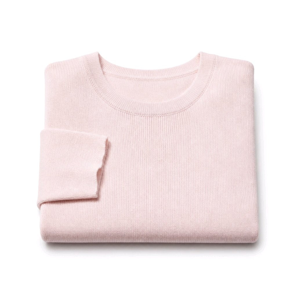 A folded light pink ribbed knit sweater on a clean white background.
